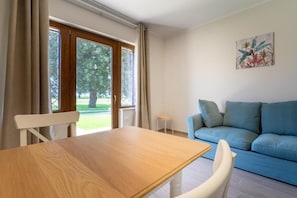 A room with a wooden table, a blue sofa, and a window with curtains.