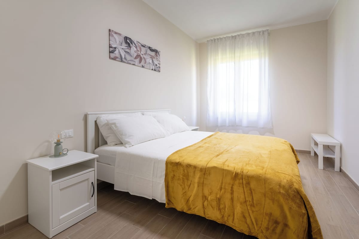 Un dormitorio con una cama, una mesita de noche y una ventana con cortinas.
