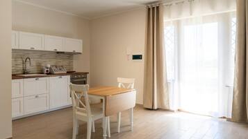 A small kitchen with white cabinets, a wooden countertop, and a dining table with chairs.