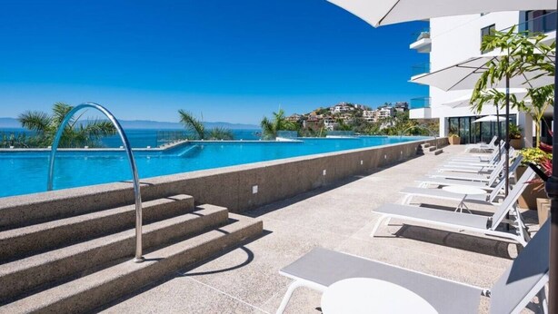 A poolside area with a clear view of the sea, steps leading to the pool, and lounge chairs. - Oceanfront 2BR Condo at Zantamar | Beachfront Pools & Luxury Amenities (La Cruz de Huanacaxtle)