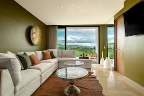 A modern living room with a sectional sofa, a round coffee table, and a balcony with a scenic view.