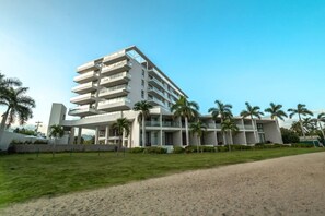 A multi-story hotel with a modern design, featuring balconies and a well-maintained lawn.