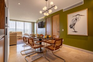 A modern dining area with a round table, wicker chairs, and a large framed bird painting on the wall.