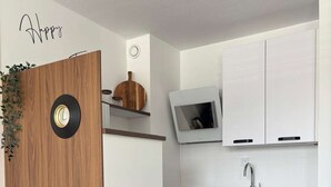 Een moderne keuken met een houten deur, een klok, een televisie en een eethoek met een gedekte tafel voor twee personen.