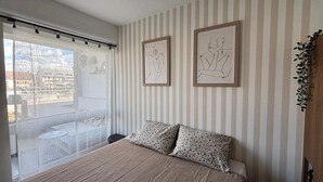 Een slaapkamer met een bed, gestreepte behang en twee ingelijste kunstwerken.