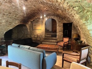 A stone-walled interior with a sofa, chairs, a table, and a fireplace. - Charming house in Provence with outbuilding - Swimming pool - 15 people (Aurons)