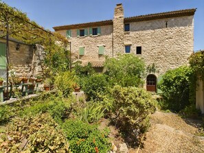 A stone building with a courtyard, potted plants, and a rustic outdoor seating area. - Charming house in Provence with outbuilding - Swimming pool - 15 people (Aurons)