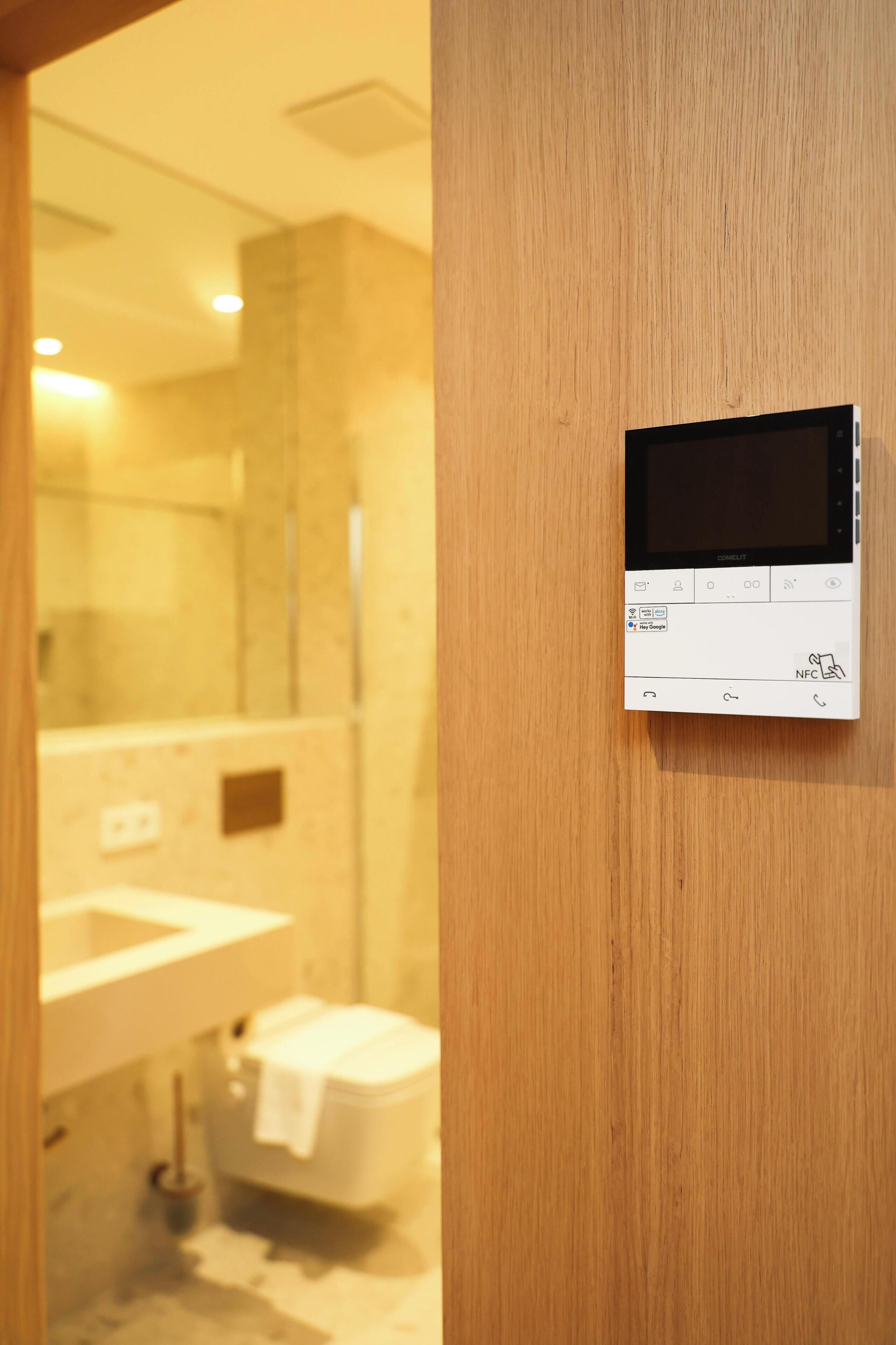 A bathroom with a wooden door, a white sink, a mirror, and a toilet.