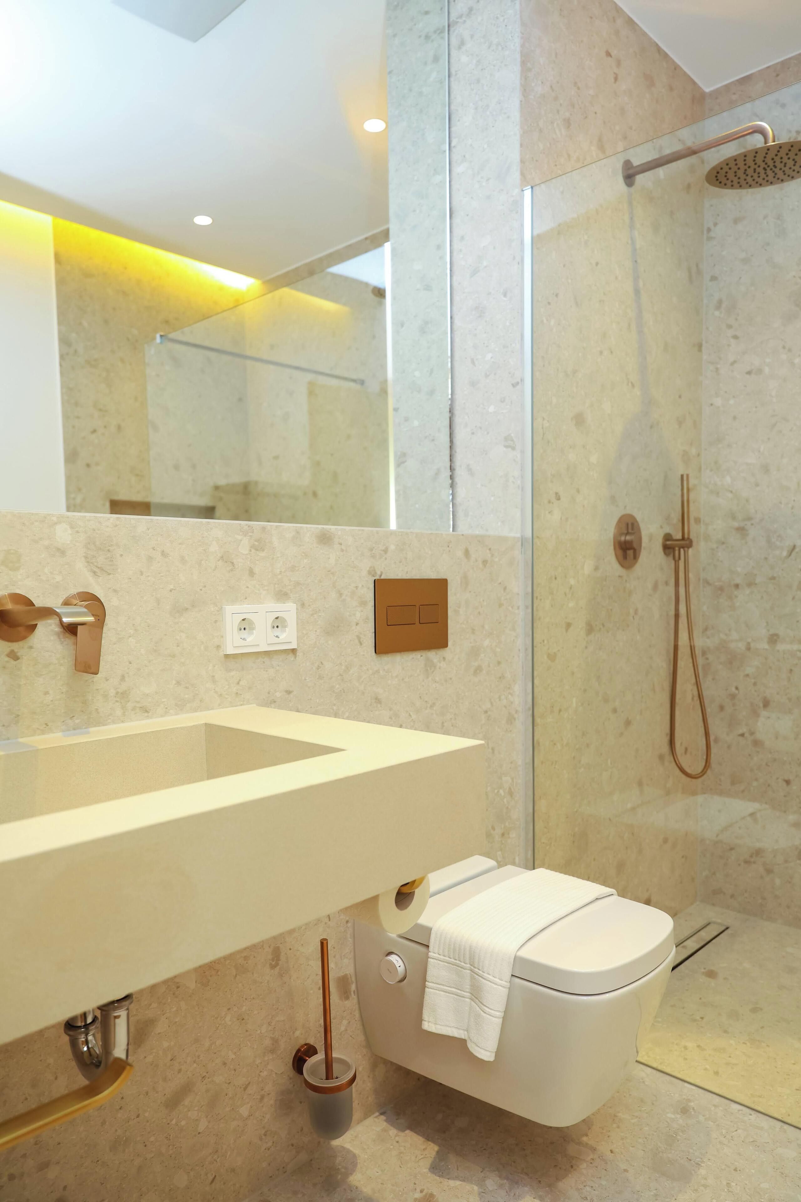 A modern bathroom with a large mirror, a sink, a toilet, and a shower.