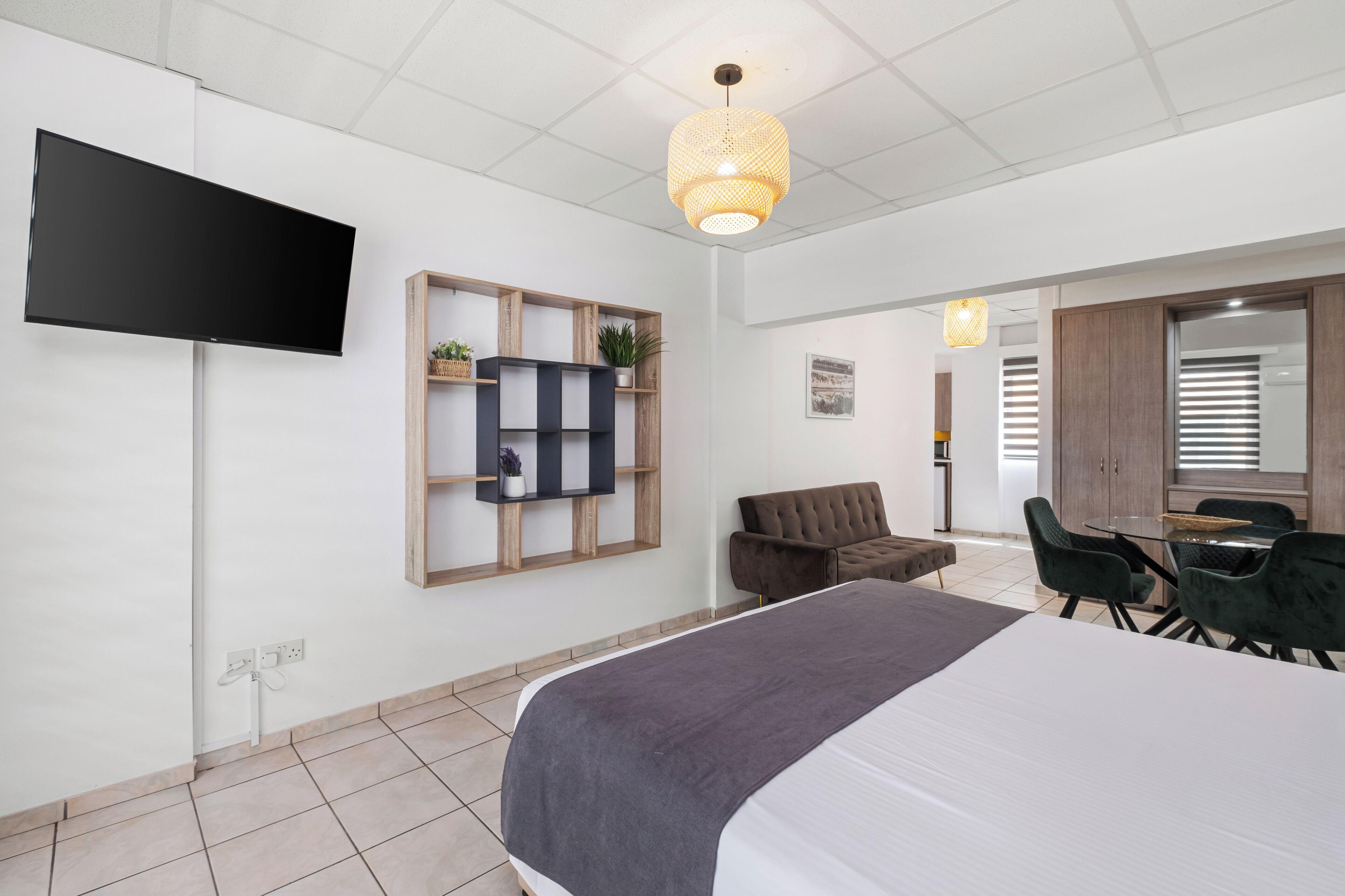 Una habitación de hotel moderna con televisión de pantalla plana, una cama, zona de comedor y kitchenette.
