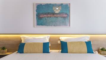 A neatly made bed with white and blue bedding, a headboard with a wooden finish, and a framed abstract painting above it.
