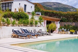 Ein Poolbereich mit Liegestühlen, einem Tisch und Stühlen.