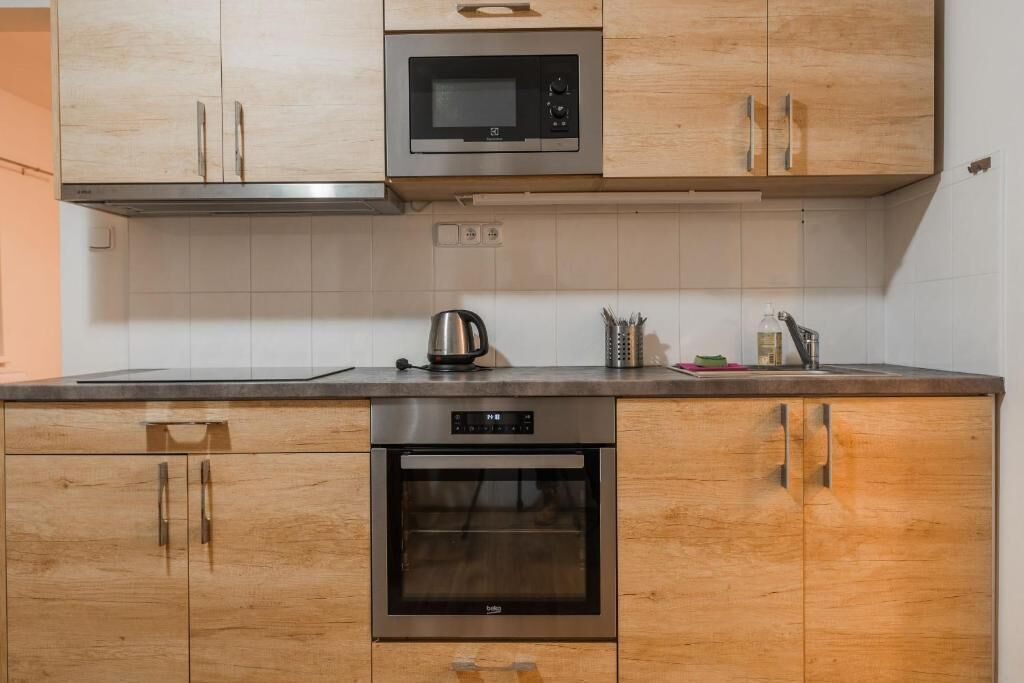 Una cocina con armarios de madera, un microondas, un horno y un hervidor.