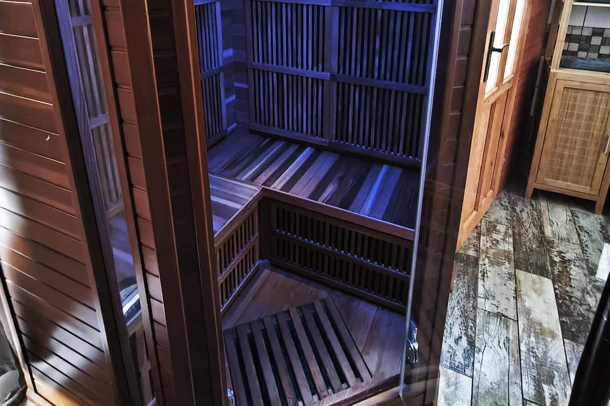 A sauna with wooden slats, a bench, and a vent at the bottom.