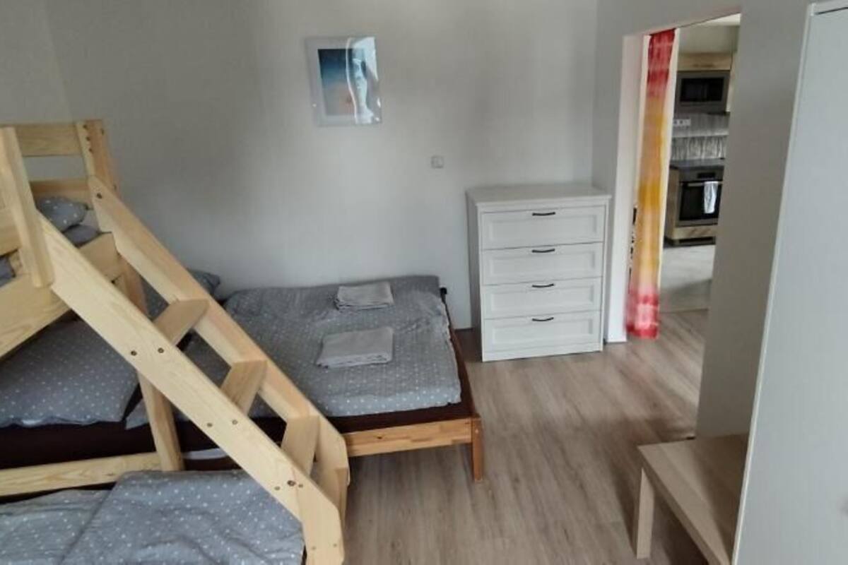 A bedroom with a bunk bed, a single bed, a white dresser, and a wardrobe.