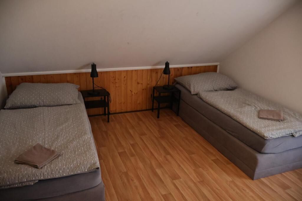 Une chambre avec deux lits, un plancher en bois et deux tables de chevet avec des lampes.