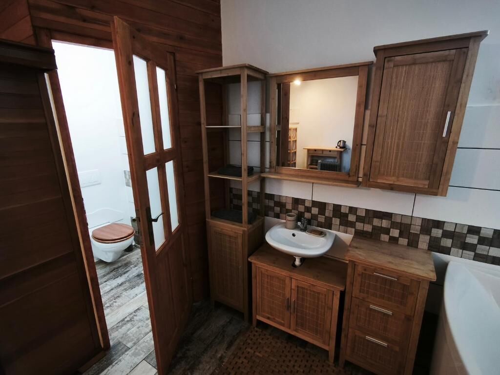 A bathroom with wooden cabinets, a sink, and a mirror.