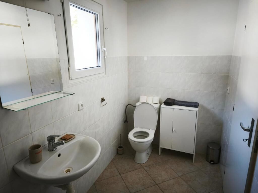 A small bathroom with a sink, toilet, and cabinet.