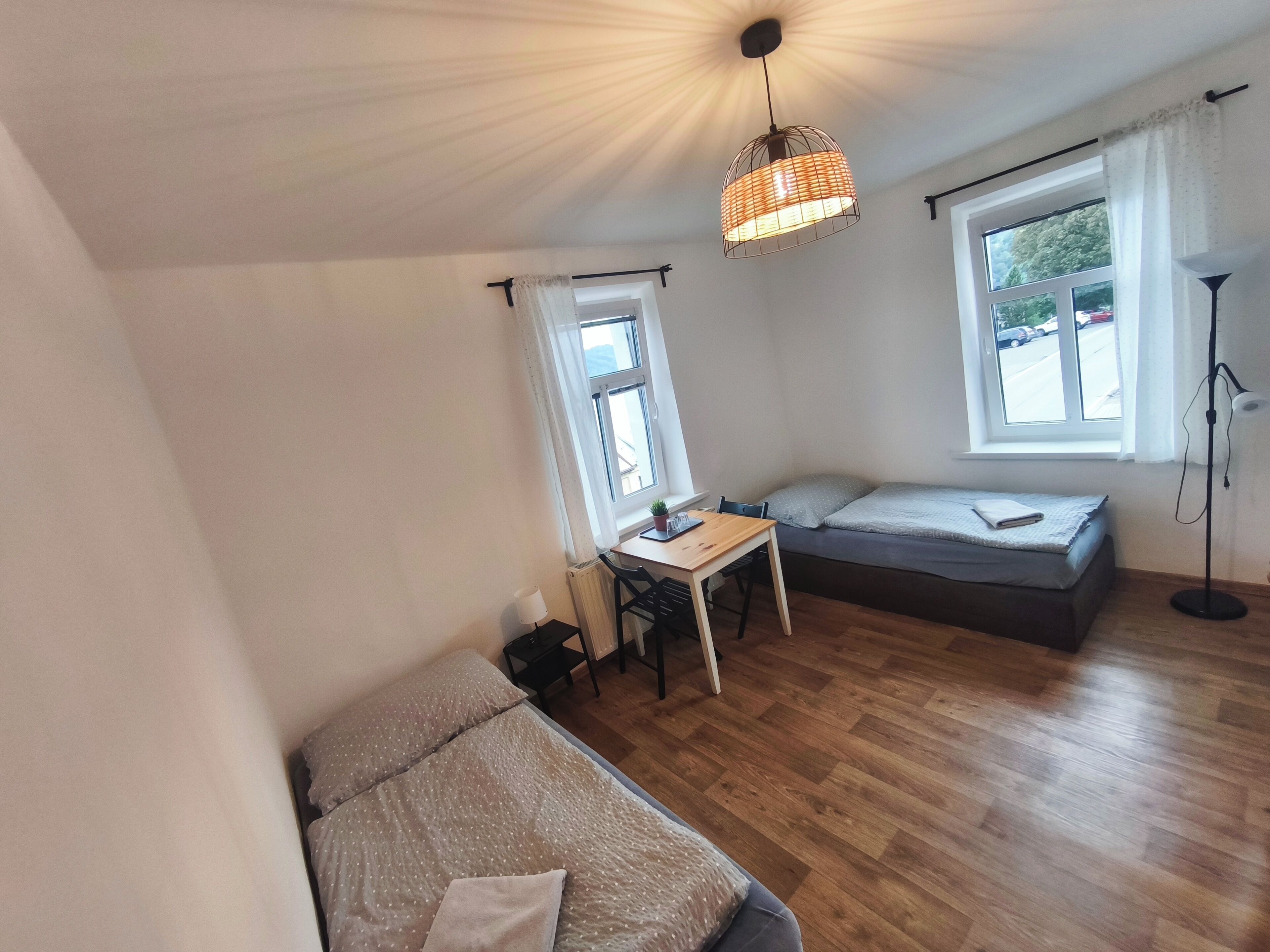 Habitación pequeña con cama, escritorio y silla. Una ventana ofrece luz natural y vistas al exterior.