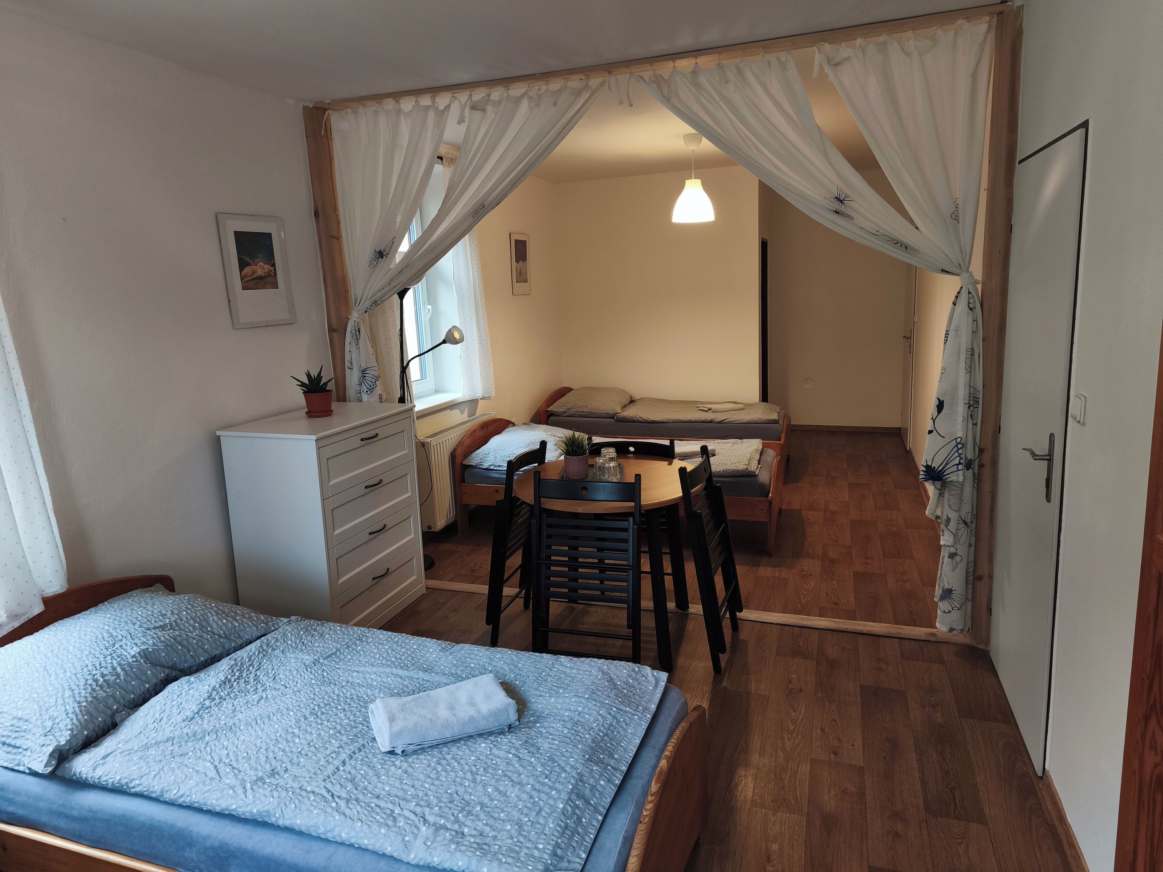 A room with a bed, a desk, and a chair, with a window and curtains.