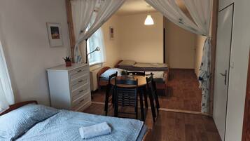 A room with a bed, a desk, and a chair, with a window and curtains.