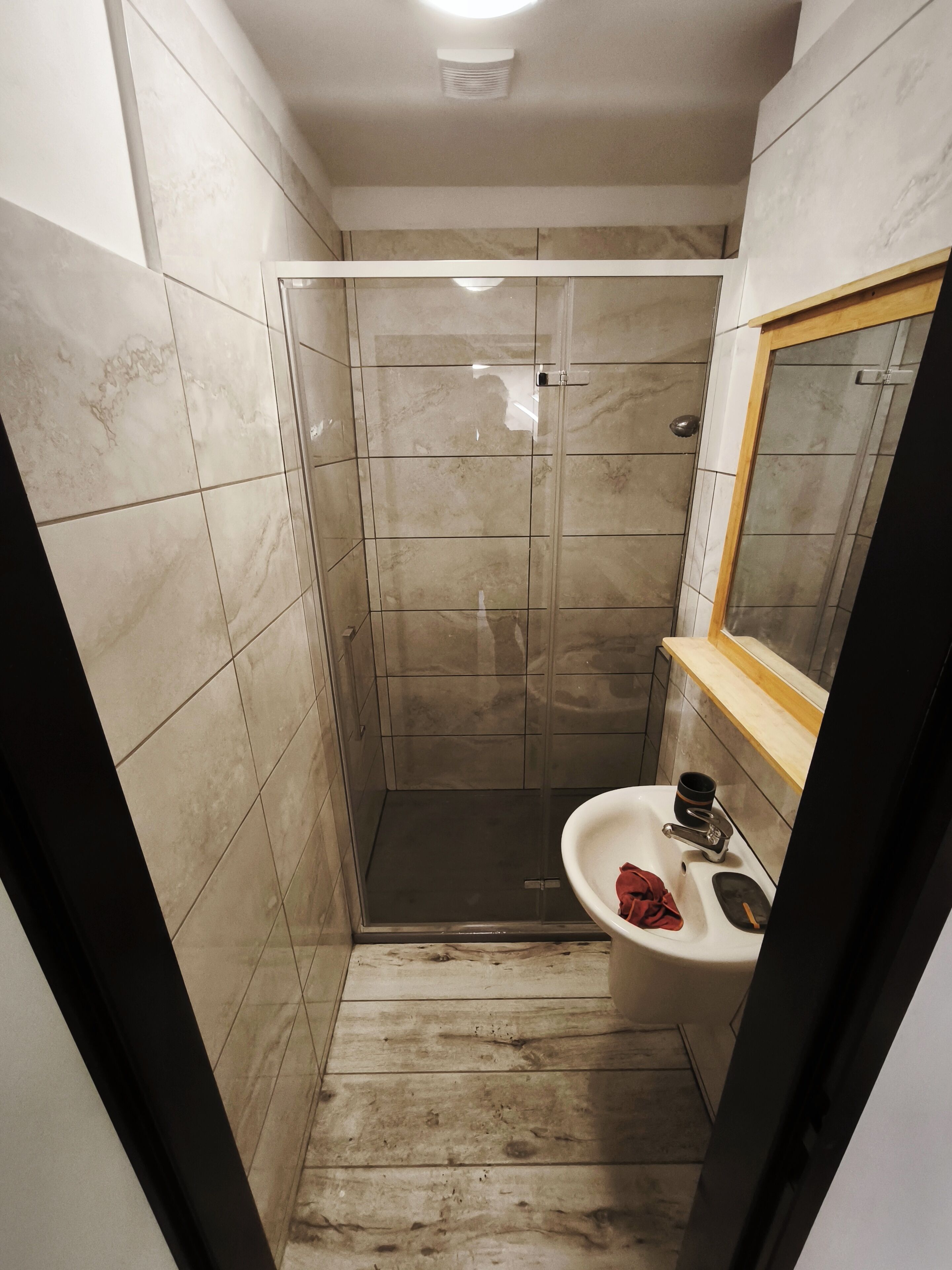 Une salle de bain avec une cabine de douche, un lavabo et un miroir.