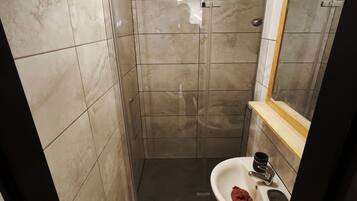 Une salle de bain avec une cabine de douche, un lavabo et un miroir.