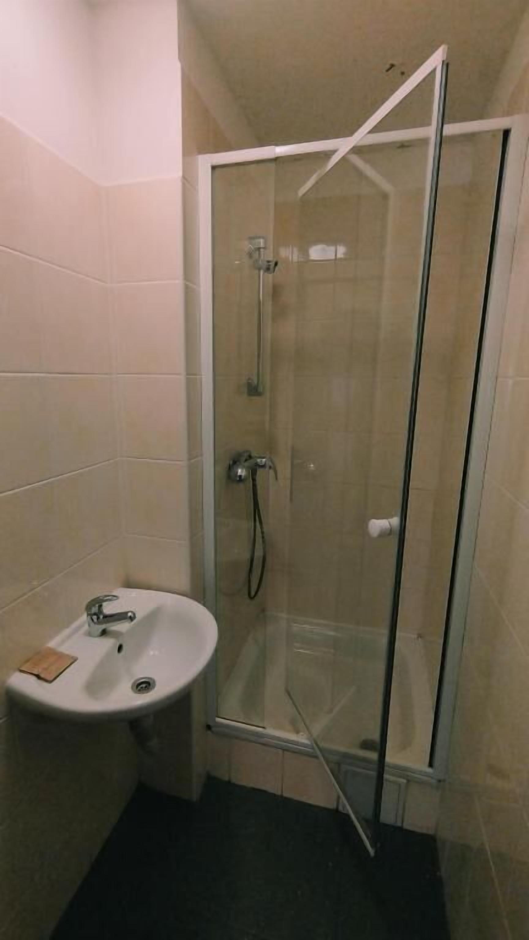 A bathroom with a glass shower enclosure, a sink, and a toilet.