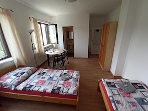 A room with two beds, a desk, and a window. - Penzion Jizera (Malá Skála)