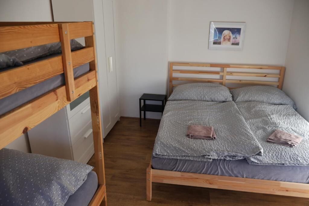 Ein Schlafzimmer mit Etagenbett, einem Einzelbett, einem kleinen Tisch und einem gerahmten Bild an der Wand.