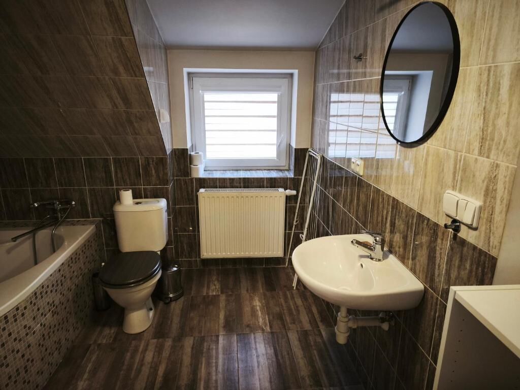 Ein Badezimmer mit Toilette, Waschbecken, Badewanne und einem Fenster.