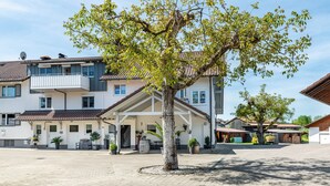 Ein Wohngebäude mit überdachter Terrasse, einem Baum in der Mitte und einem gepflasterten Innenhof.