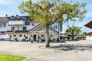 Ein Wohngebäude mit überdachter Terrasse, einem Baum in der Mitte und einem gepflasterten Innenhof.