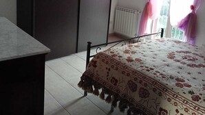 A bedroom with a bed, a wardrobe, a radiator, and a window with curtains. - THE HOUSE ON THE LAKE - App. WISTERIA - MAIELLA PARK (Abruzzo)