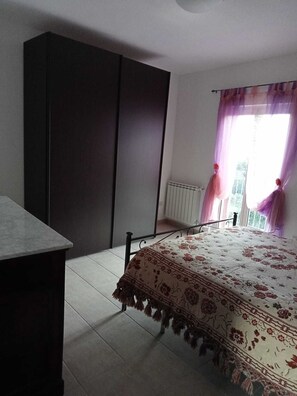 A bedroom with a bed, a wardrobe, a radiator, and a window with curtains. - THE HOUSE ON THE LAKE - App. WISTERIA - MAIELLA PARK (Abruzzo)