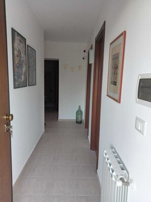A hallway with a radiator, a door, and a green bottle on the floor. - THE HOUSE ON THE LAKE - App. WISTERIA - MAIELLA PARK (Abruzzo)