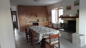 A dining area with a table and chairs, a kitchen in the background, and a fireplace. - THE HOUSE ON THE LAKE - App. WISTERIA - MAIELLA PARK (Abruzzo)