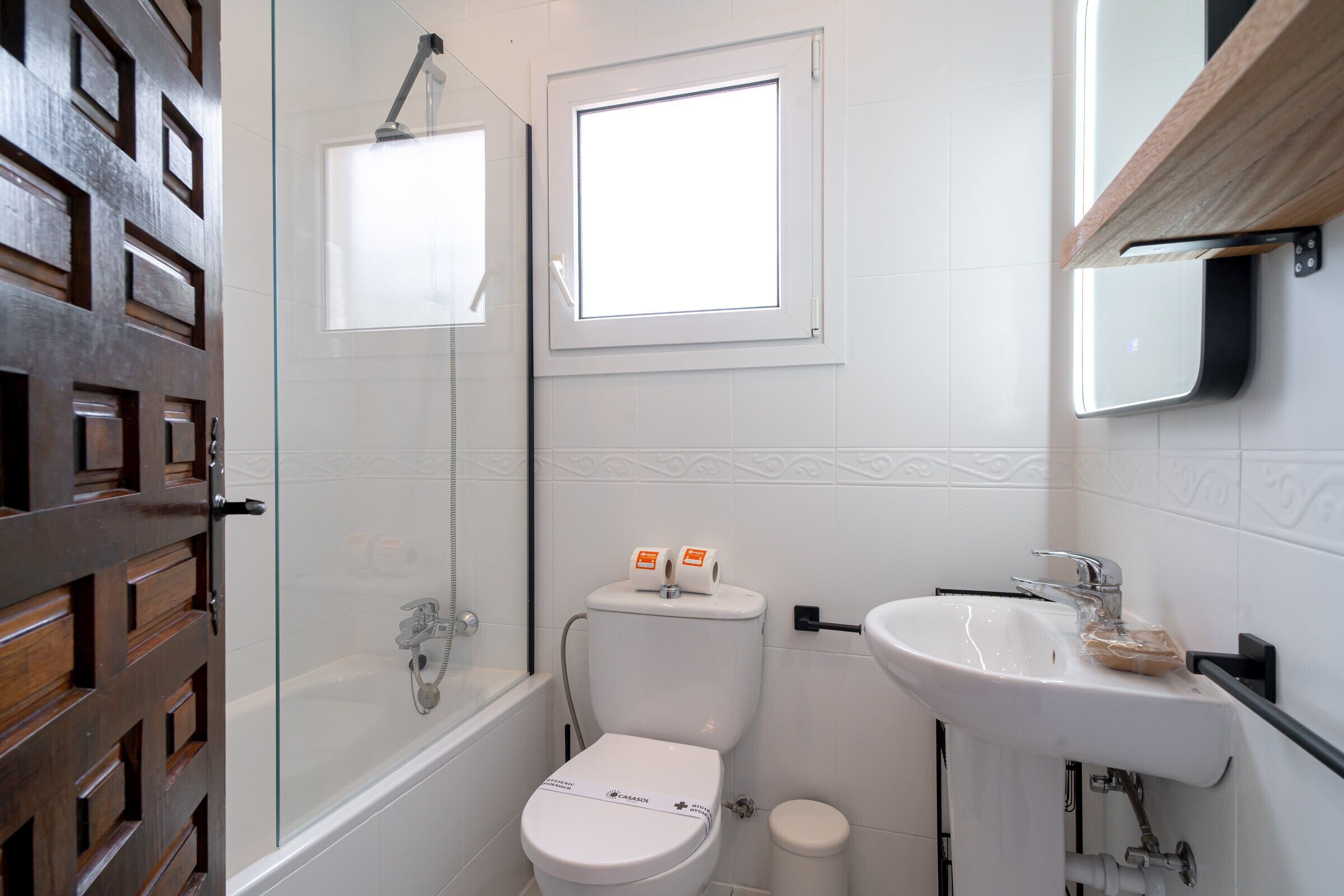 A bathroom with a toilet, a shower, a sink, and a window.