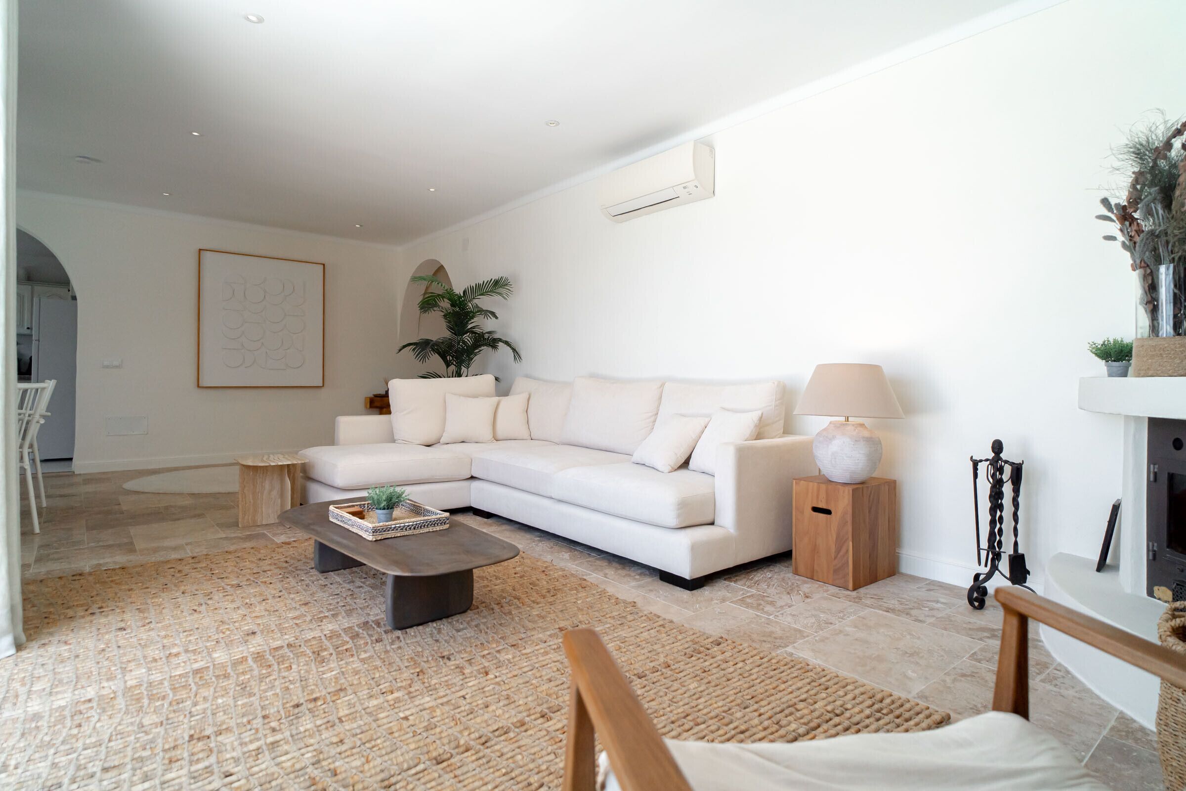 Ein modernes Wohnzimmer mit einem weißen Sofa, einem Couchtisch, einer Lampe und einem Kamin.
