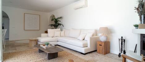 Ein modernes Wohnzimmer mit einem weißen Sofa, einem Couchtisch, einer Lampe und einem Kamin.