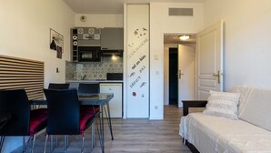 A compact living space with a kitchenette, a dining area with a table and chairs, and a bed. - Bright apartment for 4 persons with a mountain view (Grasse)