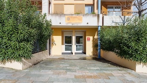 A hotel entrance with a yellow facade, double doors, and a sign indicating 'Hotel & Residence.'