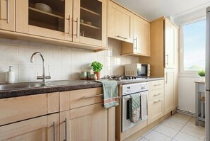 Eine moderne Küche mit Holzausstattung, einem Edelstahlspülbecken, einer Mikrowelle und einem Herd.