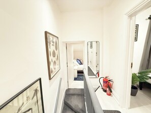 Ein Flur mit Treppe, einem Feuerlöscher und einer Tür zu einem Raum.