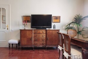 Una sala de estar con un mueble de madera, un televisor, un sillón y una planta.
