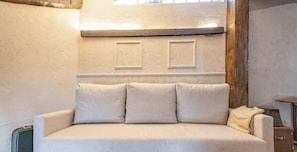 Un sofá blanco con tres cojines frente a una pared con dos paneles rectangulares.