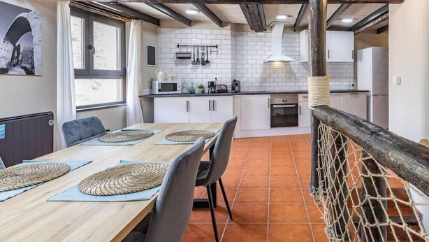 A compact kitchen with white cabinets, a microwave, and a hanging light fixture.