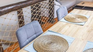 A wooden table with woven placemats and a chair with a cushioned backrest.