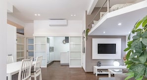 Una sala de estar moderna con televisor, asientos y una escalera.
