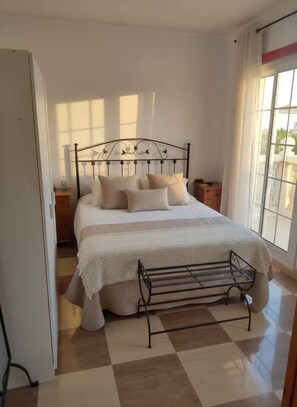 Un dormitorio con cama, ventana, radiador y suelo a cuadros.